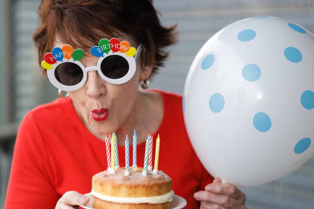 woman-with-happy-birthday-glasses-blowing-out-candles-on-a-birthday-picture-id1165027849
